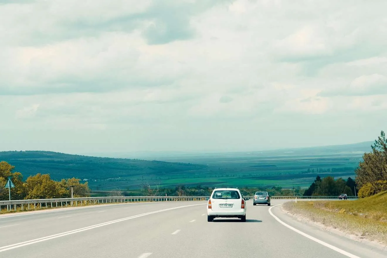 Baltas automobilis greitkelyje tarp laukų