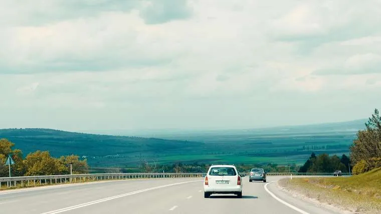 Baltas automobilis greitkelyje tarp laukų
